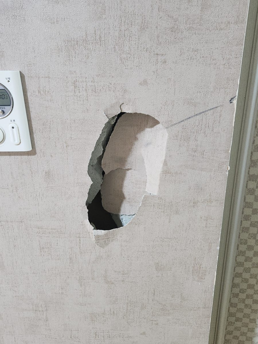 온도조절기 옆 벽이 크게 뚫려 석고보드가 드러난 상태 - 작업 전