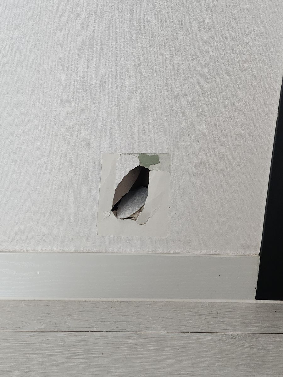 걸레받이 위 석고벽이 뚫리고 벽지가 찢어진 모습 - 작업 전