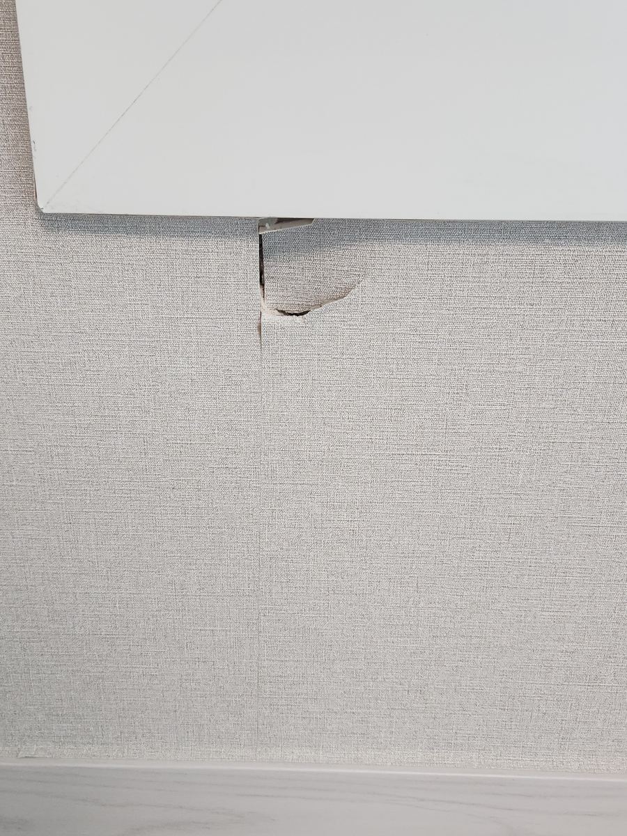 의자 다리에 찍혀 벽지가 찢어지고 석고벽이 파손된 모습 - 작업 전